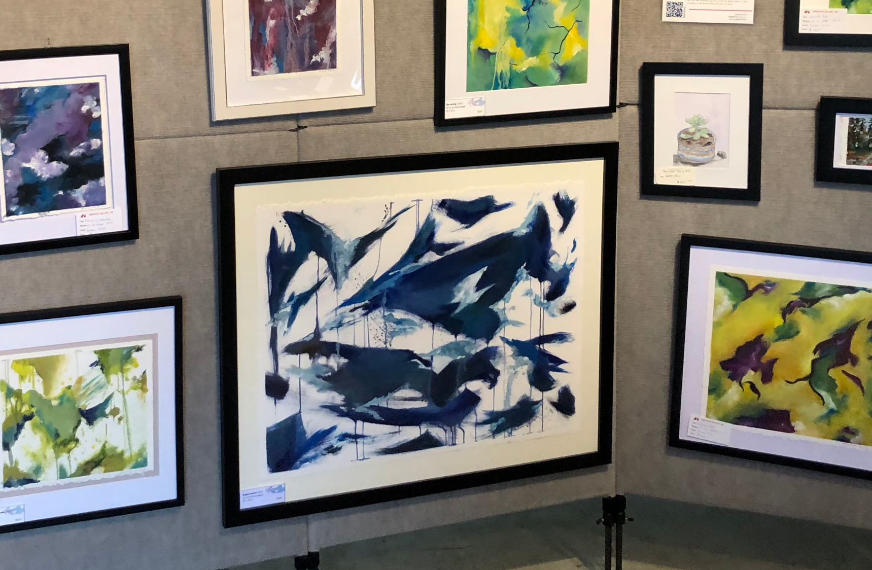 Large framed abstract blue watercolor painting displayed on gallery wall