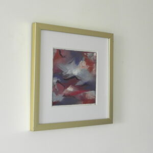 Framed abstract art print with red, blue, and white hues in a gold frame