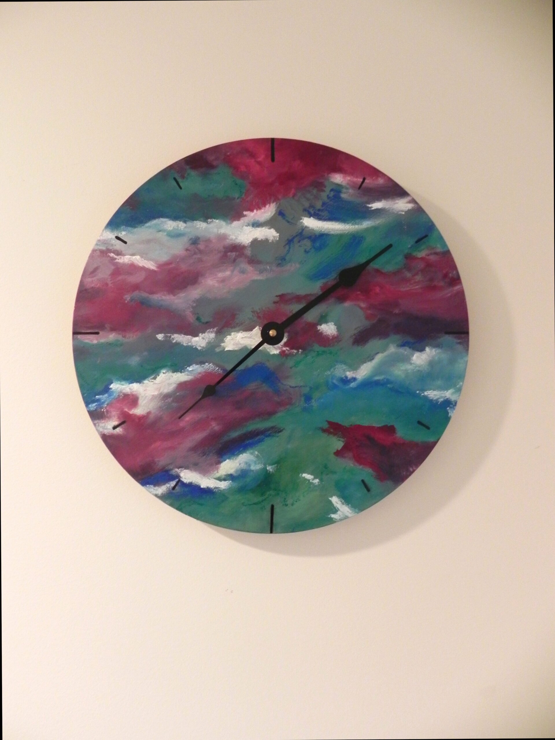 Round wall clock with abstract painted face in pink, teal, and white colors
