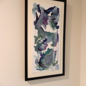 Framed abstract watercolor painting with blue, green, and purple hues on a white wall