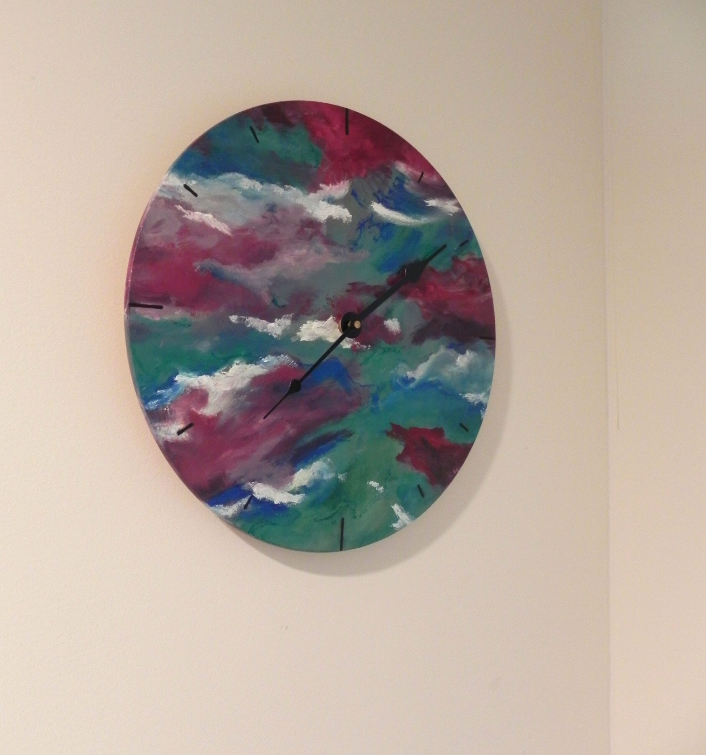 Round wall clock with abstract painted face in teal, magenta, and white