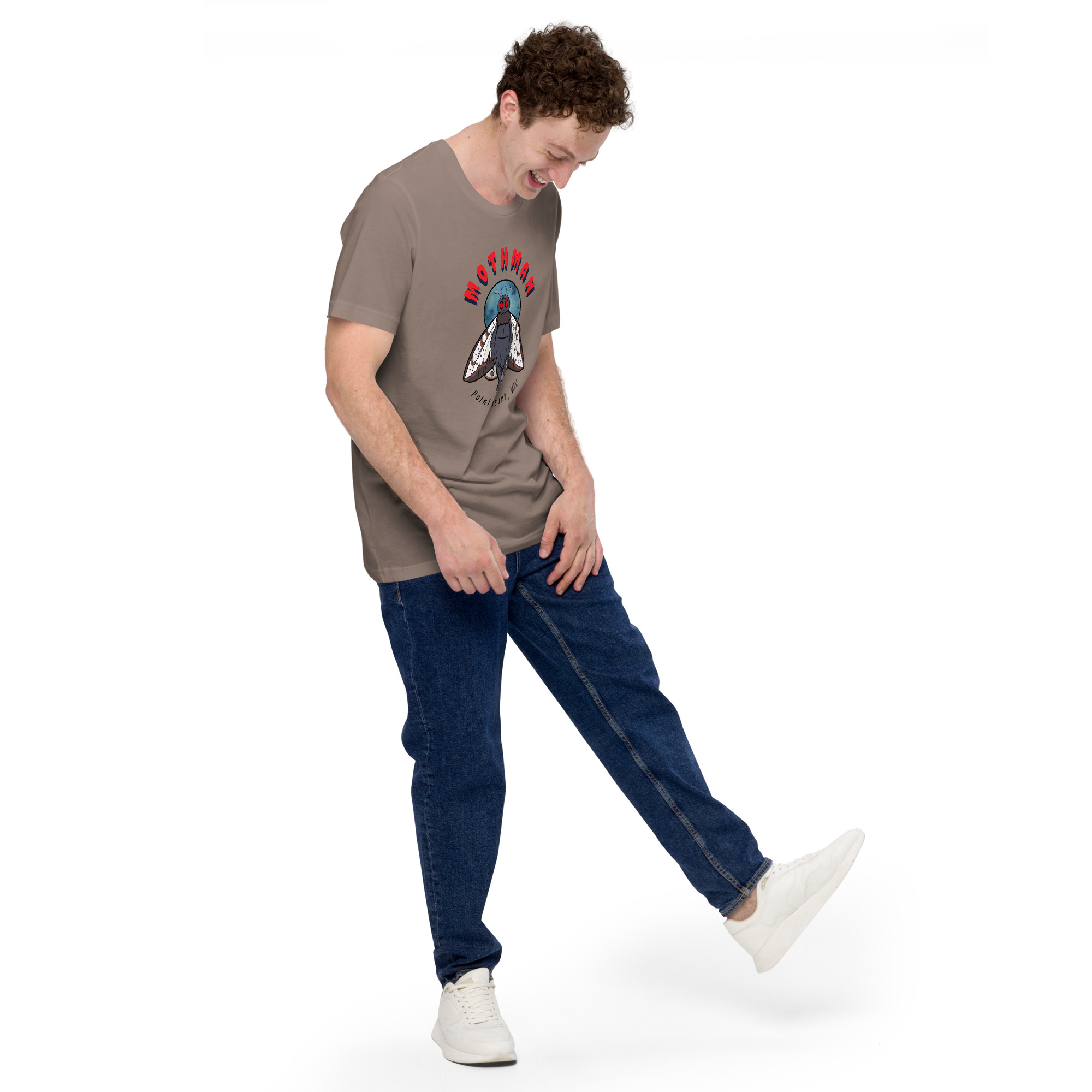 Man wearing brown Mothman graphic t-shirt and blue jeans laughing while kicking leg up