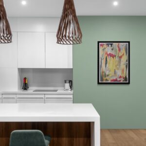 Abstract artwork featuring bold drips of red and yellow in a black frame hanging on a sage green wall above a white kitchen island with pendant lights.