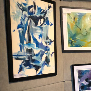 Framed abstract watercolor painting with blue and black brushstrokes on gallery wall