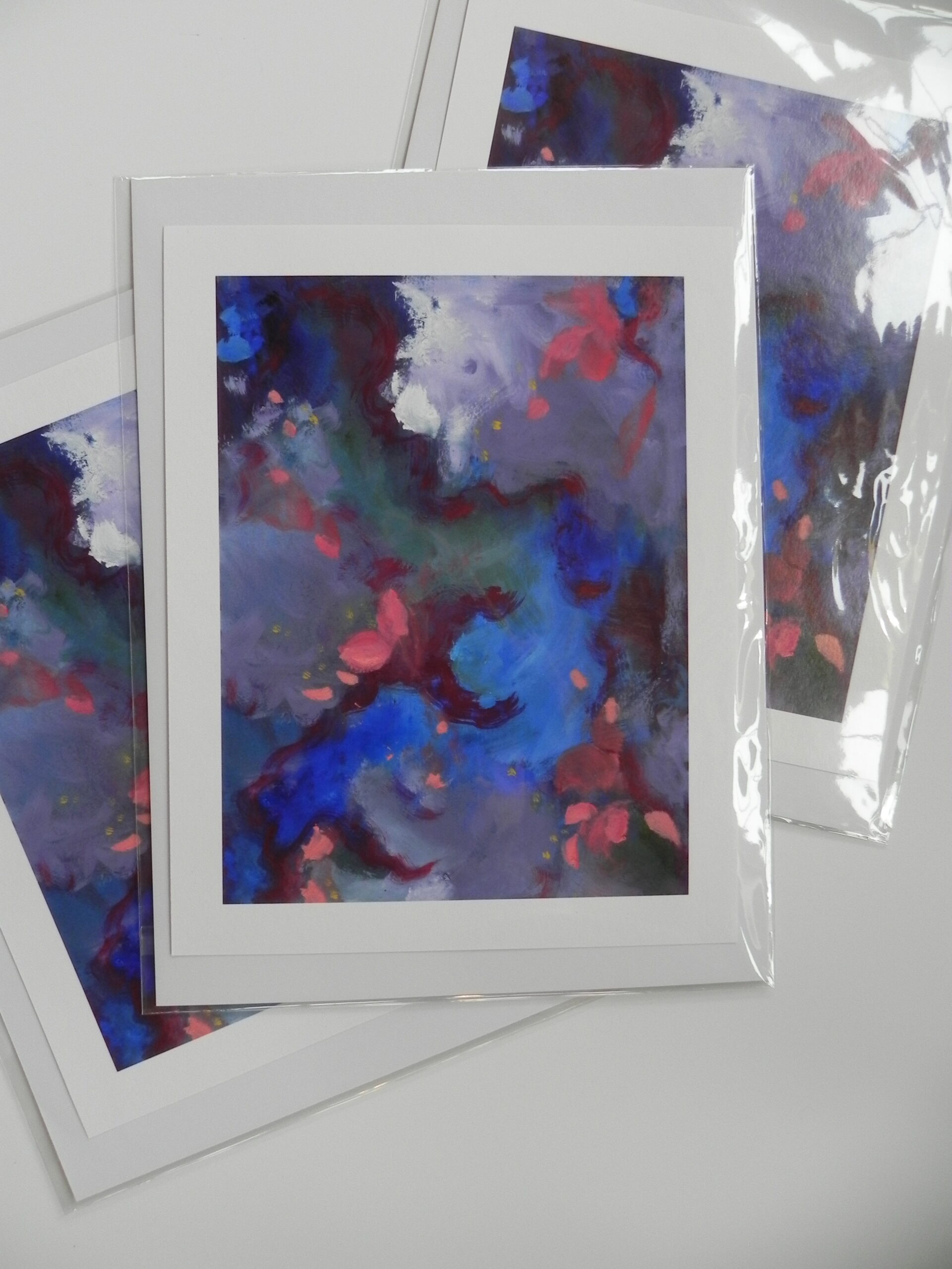 Abstract art print with blue, red, and white brushstrokes in white mat and plastic sleeve