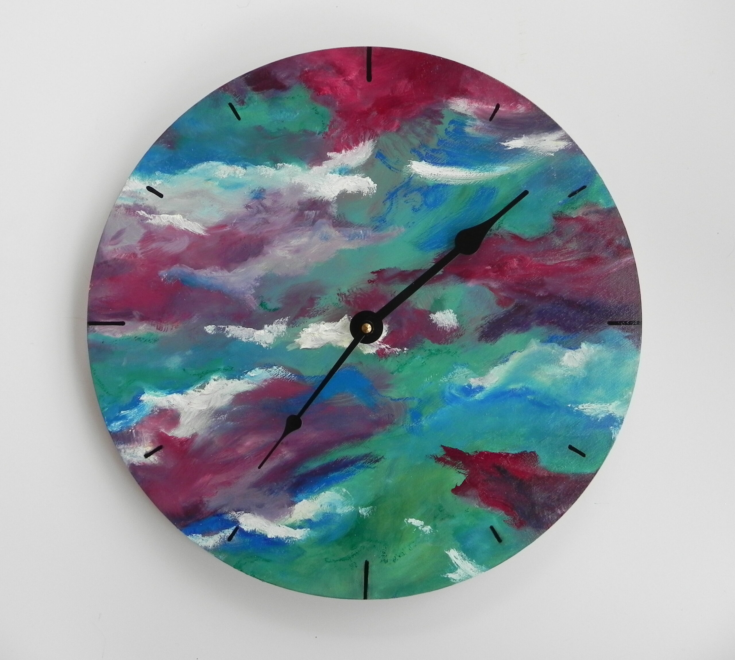Round wall clock with abstract painted face in teal, magenta, and white with black hands