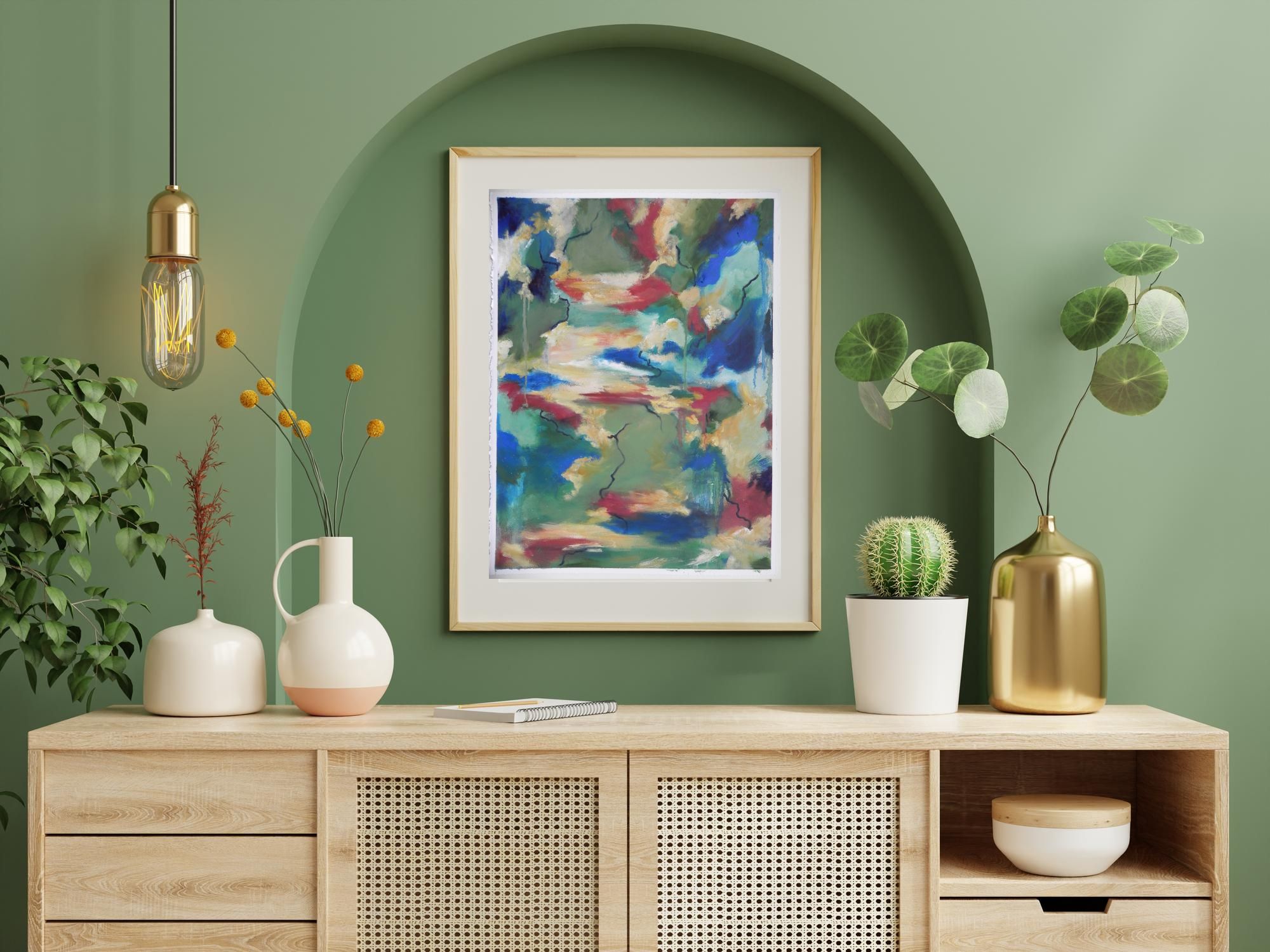 Framed abstract art print with blue, red, and green hues hanging above a wooden console table
