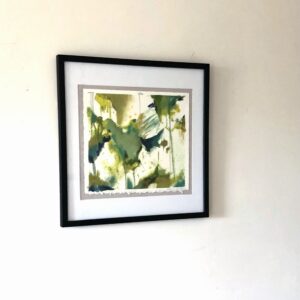 Framed abstract watercolor print with green and white tones on white wall