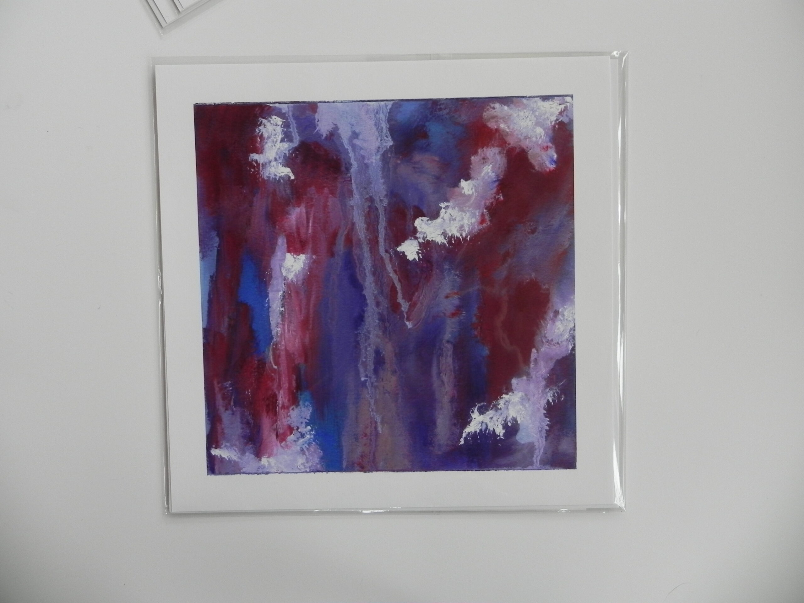 Abstract art print with red, blue, and white vertical brushstrokes in white mat and clear frame