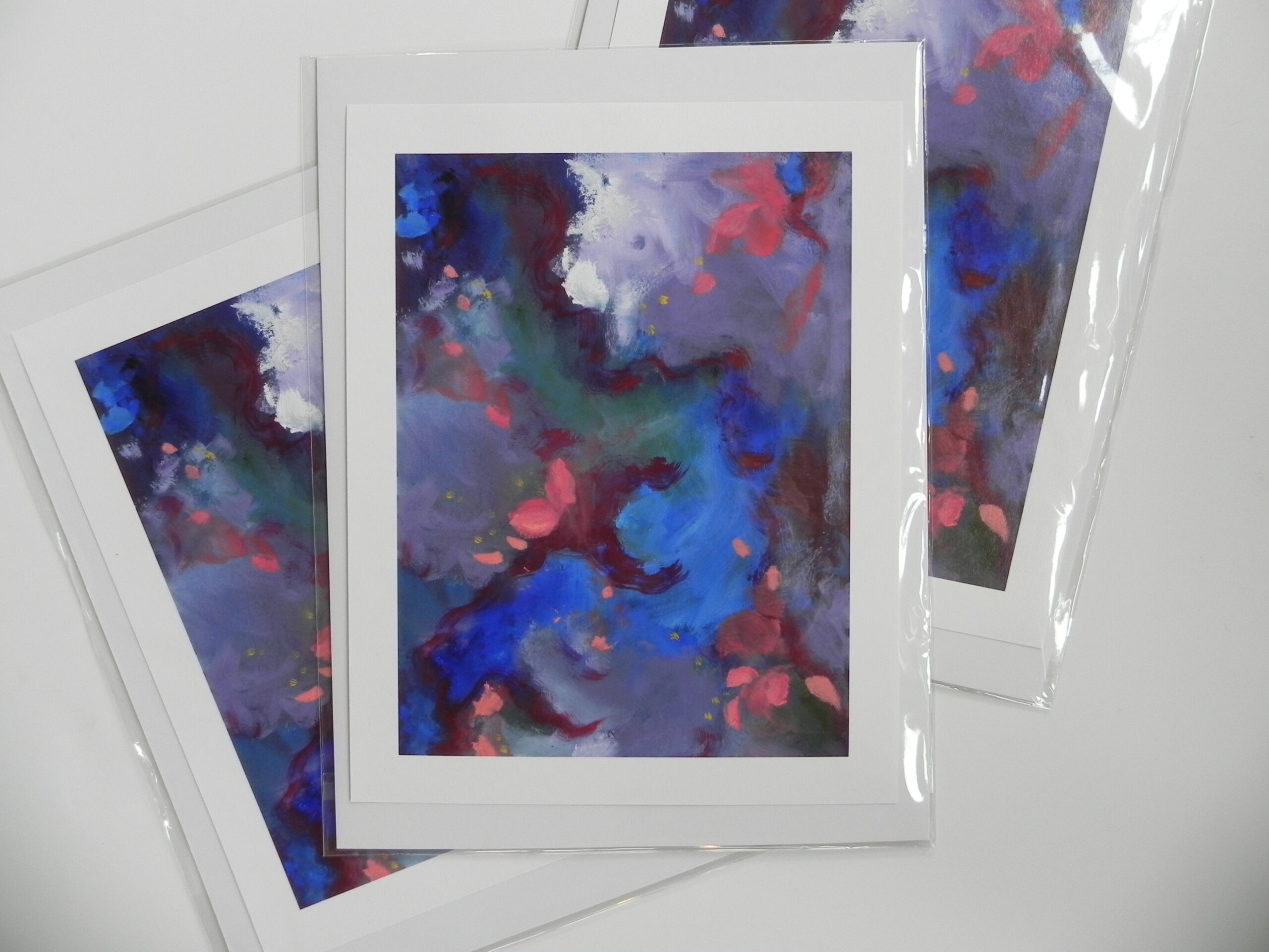 Abstract art print with blue, purple, and red hues in white matting and plastic sleeve