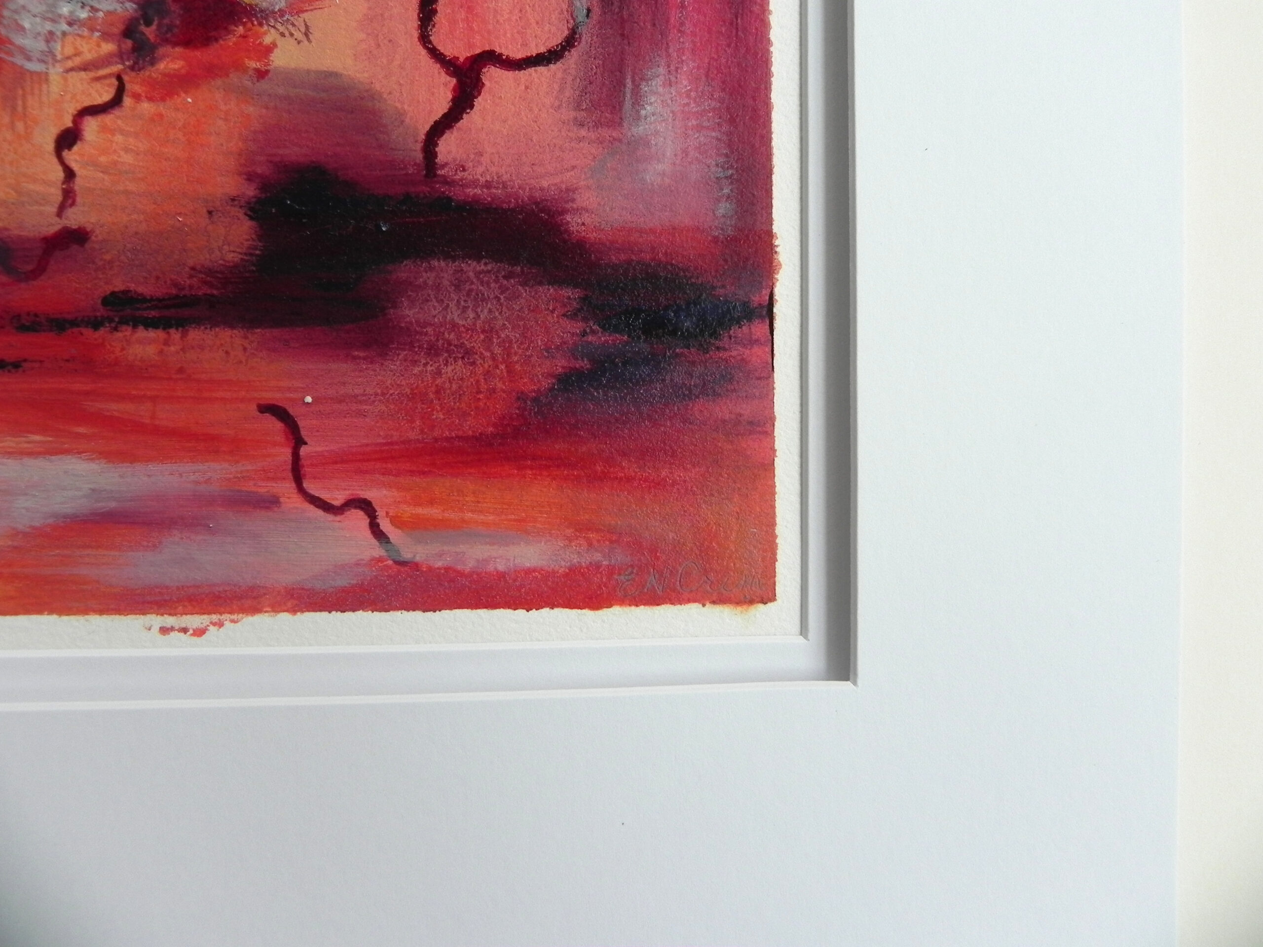 Abstract painting with bold red and orange tones and dark linear accents, presented in a white frame with wide matting