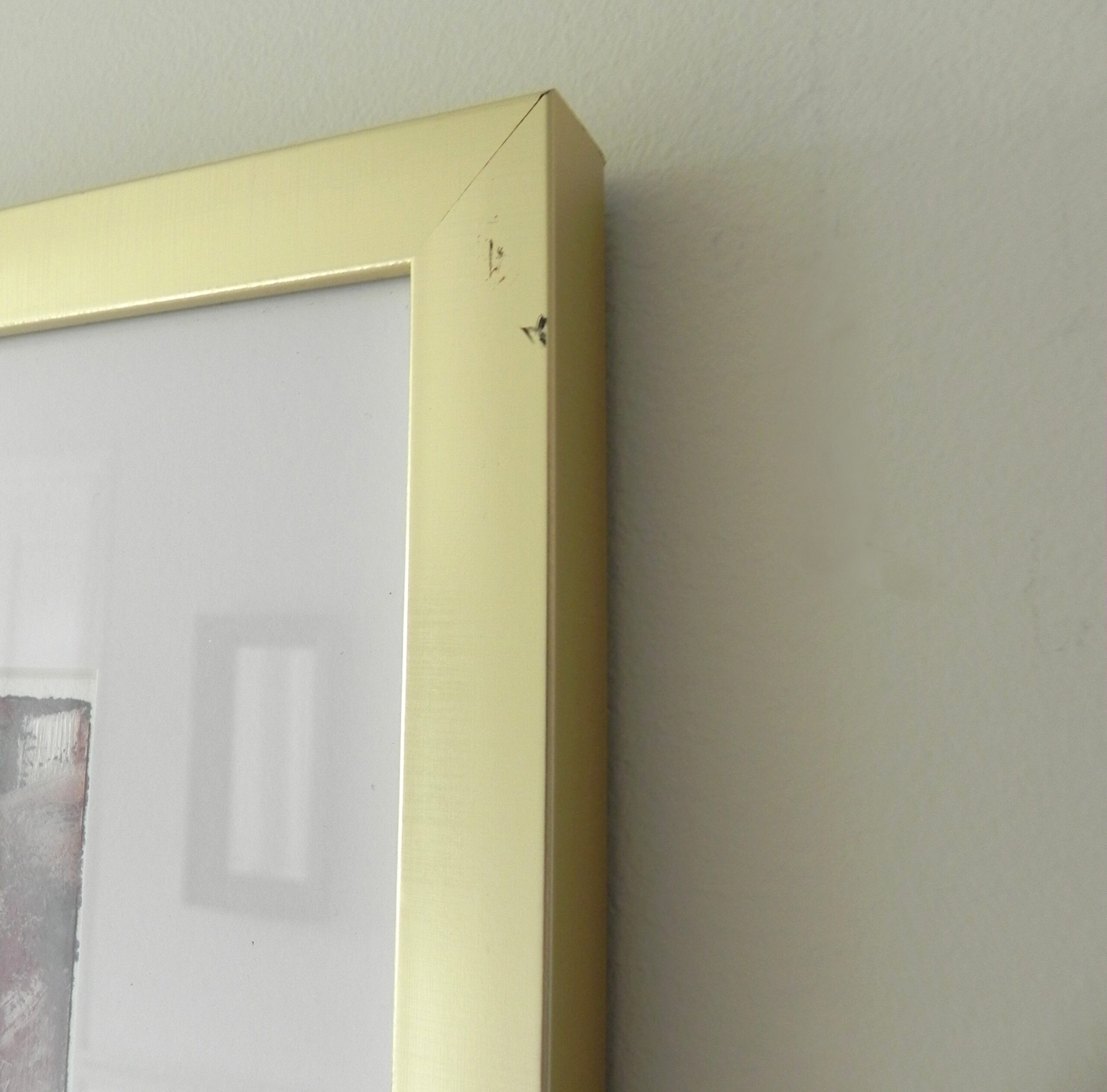 Close-up of pale yellow picture frame corner showing minor surface damage
