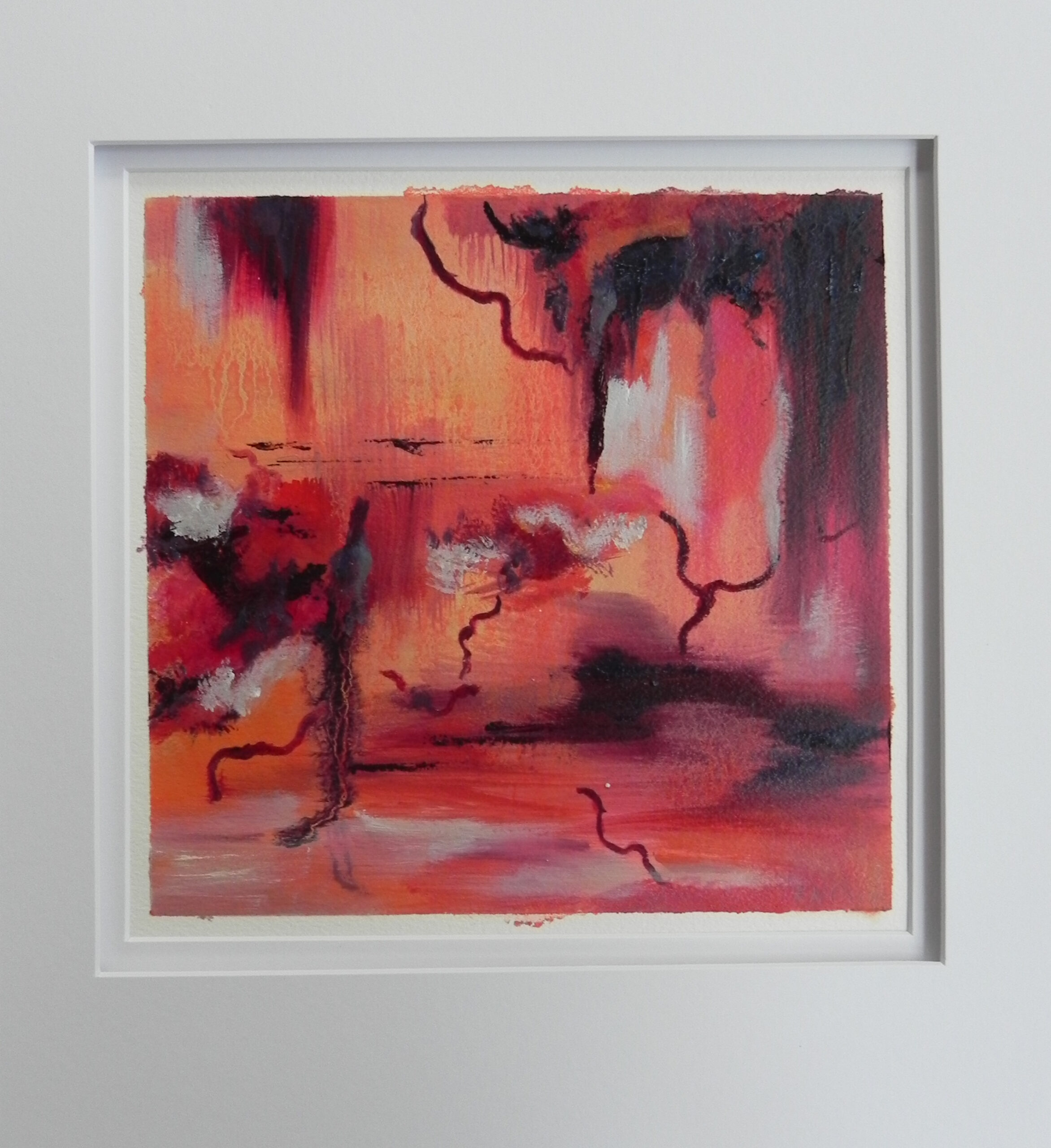 Framed abstract painting with red, orange, and black brushstrokes on white wall